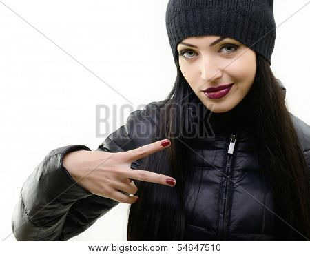 portrait of beautiful cool girl gesturing in black hat and jacket over white