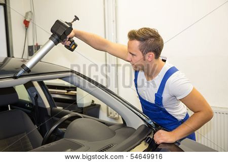 Glazier With Application Gun In Garage Replacing Windshield Or Windscreen