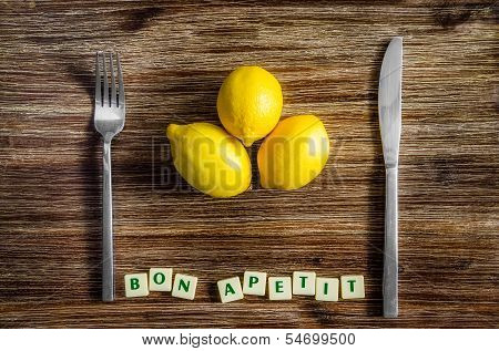 Silverware And Lemons On Wooden Table With Bon Apetit Sign