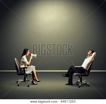 smiley man listening angry woman over dark background