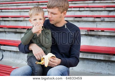 Little boy eating banana with his father