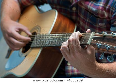 close up of a male musician playing acoustic guitar