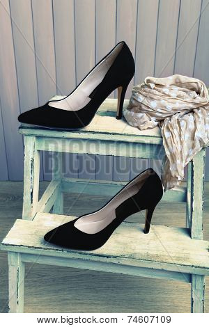 Black women shoes and scarf on bench on wooden background