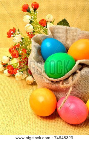 Easter Colored Eggs In The Sack With Flowers