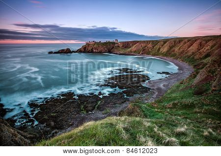A rocky beach under a crumbling castle in England