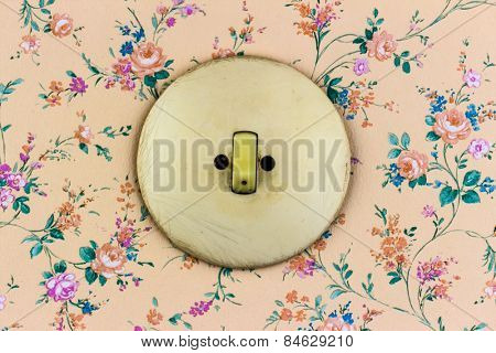 an old wallpaper with light switch. symbolic photo for renovation and remodel.
