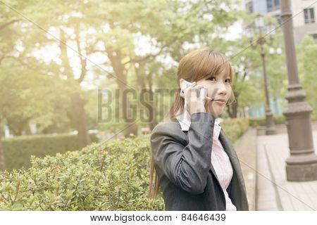 Asian business woman use cellphone in modern city, closeup portrait shot at Xinyi business district, Taipei, Taiwan.