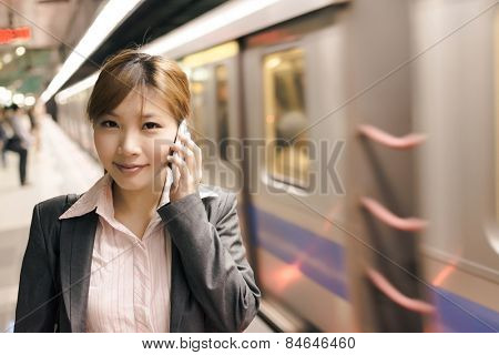 Asian young business woman use cellphone in the MRT station, shot at Xinyi business district, Taipei, Taiwan.
