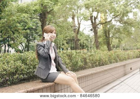 Asian business woman use cellphone in modern city, closeup portrait shot at Xinyi business district, Taipei, Taiwan.