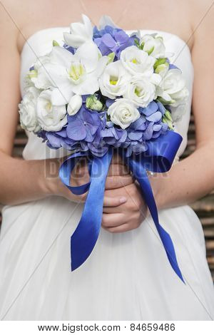 Beautiful wedding bouquet of hydrangea, eucharis and eustoma flowers in hands of the bride
