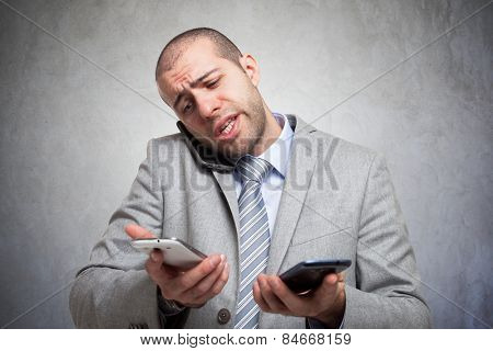 Stressed businessman talking on many phones at once