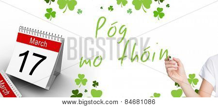 Female hand holding black whiteboard marker against shamrocks