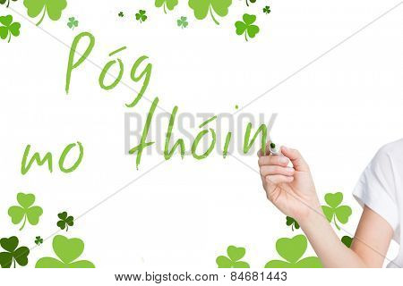 Female hand holding black whiteboard marker against shamrocks