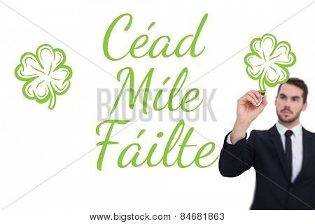 Thoughtful businessman writing with marker against shamrock