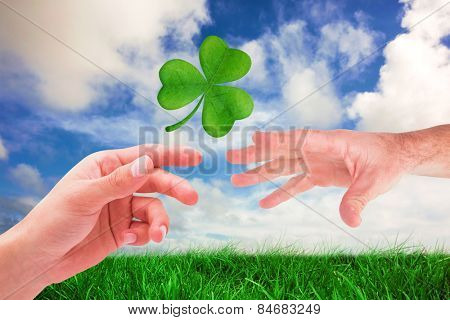 Businessman holding his hand out against green grass under blue sky