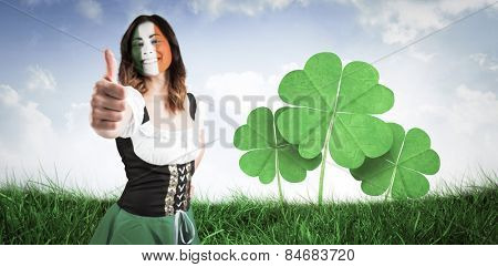 Irish girl showing thumbs up against field of grass under blue sky