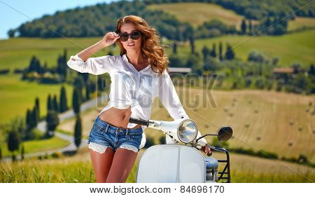 Young beautiful italian woman sitting on a italian scooter in tuscany outdoor 