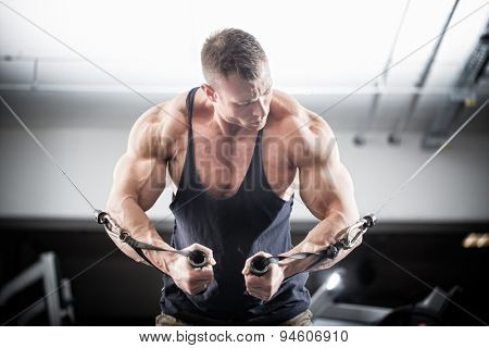 Bodybuilder doing butterfly on cable pull for better definition of his arm muscles