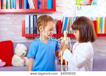 Cute Kids Playing In Doctors With Toy Human Skeleton