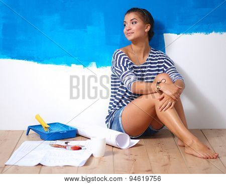 Portrait of female painter sitting on floor after painting.