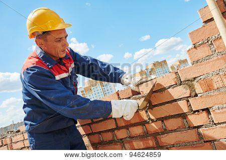 construction worker. mason bricklayer installing red brick with trowel putty knife outdoors
