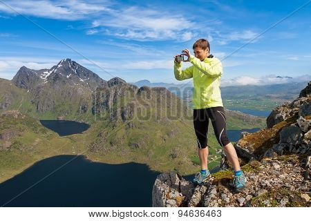 Sporty woman on the top of a mount Holandsmelen making photo Lofoten Norway