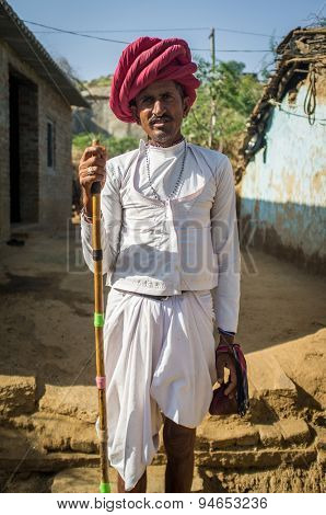 GODWAR REGION, INDIA - 13 FEBRUARY 2015: Rabari tribesman stands in courtyard in traditional clothes and holds herding stick. Rabari or Rewari are an Indian community in the state of Gujarat.