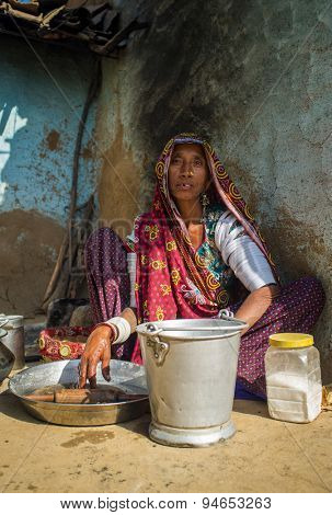 GODWAR REGION, INDIA - 13 FEBRUARY 2015: Rabari tribeswoman in sari decorated with traditional upper-arm bracelets cleans dishes. Rabari or Rewari are an Indian community from Gujarat.