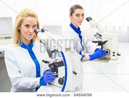 Two medical workers working with microscope