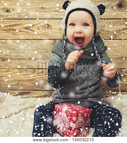 Little girl smiling with gift box.Iit's snowing.