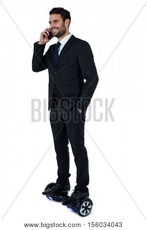Businessman on hoverboard talking on mobile phone against white background