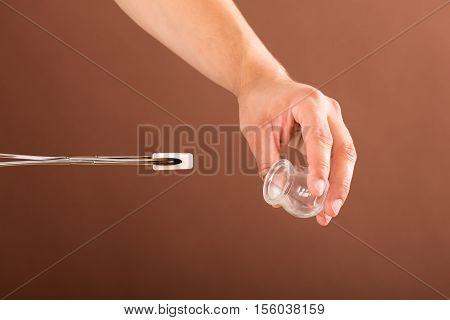 Close-up Of A Therapist Holding Lit Camphor With Tong And Cup In Spa