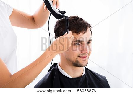 Smiling Young Man Getting His Haircut From Hairdresser At Salon