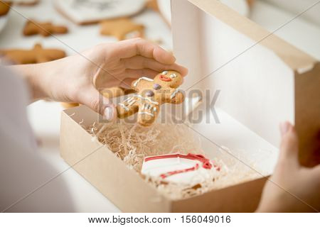Close up of confectioner hand packing an amazing traditional Christmas gingerman into a cardboard craft box. Christmas concept photo, lifestyle