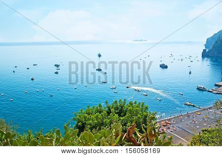 The view from the on the coast cozy beach numerous yachts and boats in Marina Grande harbor lush greenery of local gardens Positano Italy.