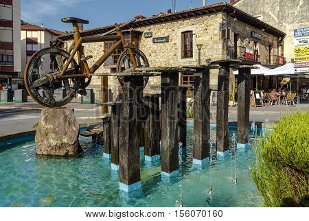 Cabezon De La Sal Spain - August 24 2016: Bicycle roundabout in the Plaza de la Paz in the Cantabrian town a monument made in wood with wheels of carriage. Decorate the roundabout also a fountain and various aromatic plants such as rosemary and lavender.