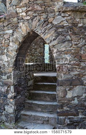 Fragment of ancient stone walls of fortress with arched entrance and stone staircase leading to the courtyard. Reichenstein Castle Rhine Valley Germany - UNESCO World Heritage
