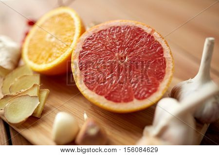 traditional medicine, cooking, food and ethnoscience concept - citrus fruits, ginger and garlic on wooden background
