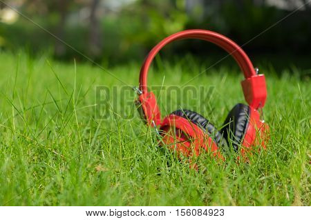 Red Headphones on green grass selective focus.