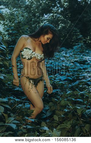 Sensual young brunette with closed eyes outdoors in the wood in underwear leaf