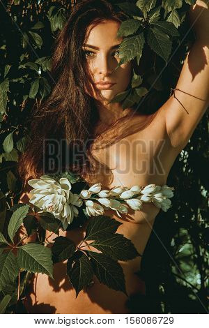 brunette girl in underwear leaf looking at the camera outdoors in the forest
