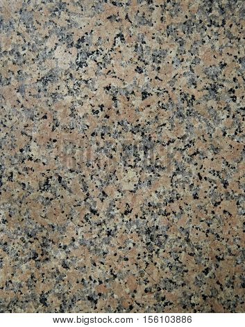 Granite Blacksmith. Natural stone texture with pink-red color with a lot of black inclusions. The surface of the building material for finishing floors and walls fireplaces and staircases