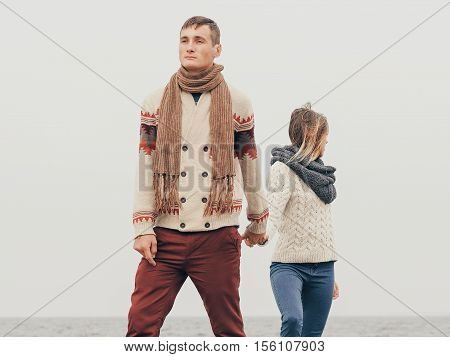 Young attractive couple in knitted sweaters on a cliff on sea shore hugging and holding hands creative toning