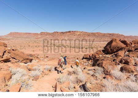 Twyfelfontein, Namibia - August 27, 2016: Group Of Tourists Walking In The Desert At Twyfelfontein,