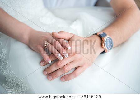Hands newlyweds with a bouquetA newly weding couple place their hands on a wedding bouquet