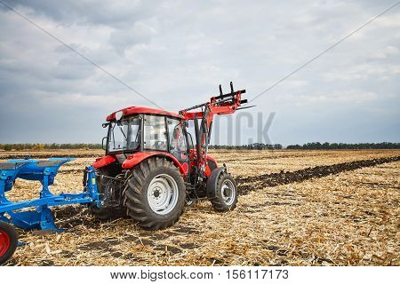 Farmer riding a tractor, a tractor working in a field, agricultural machinery in the work, tractor in the background cloudy sky