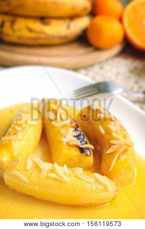Bananas flambe with nuts on a white plate