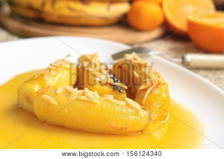 Bananas flambe with nuts on a white plate
