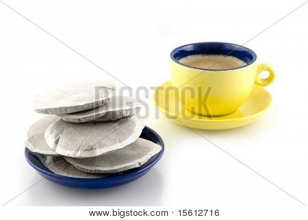 um Pires cheio de pastilhas de café com uma xícara de café