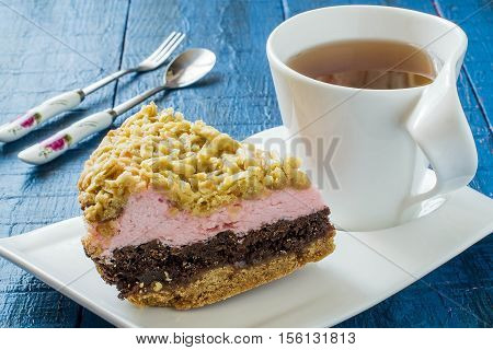 Baking in multicooker. Homemade festive multilayer cake with jam chocolate marshmallows streusel and a cup of tea on a blue wooden background. Selective focus